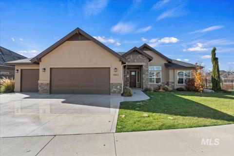 View of front of house with stone siding, an attached garage, stucco siding, and a front yard