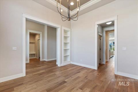Unfurnished dining area with a chandelier, light wood-style flooring, built in features, recessed lighting, and a raised ceiling