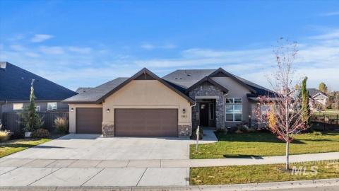 View of front of home featuring stone siding, stucco siding, an attached garage, and driveway