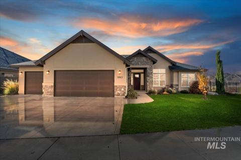 View of front facade with stone siding, a garage, stucco siding, a lawn, and driveway