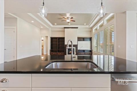 Kitchen featuring white cabinets, dark stone countertops, a tray ceiling, and recessed lighting