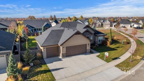 View of front of home featuring an attached garage, a residential view, driveway, and stone siding
