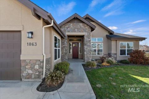 Entrance to property featuring stone siding, a yard, and stucco siding