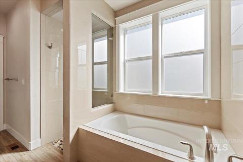 Bathroom featuring a stall shower, a bath, and wood finished floors