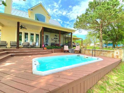 This is a charming home featuring a spacious wooden deck with an integrated small pool/spa, perfect for relaxation. The covered patio area offers ample space for outdoor dining and lounging, overlooking a serene, tree-lined backyard.