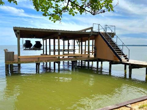 This is a waterfront property featuring a spacious private dock with a covered boat lift and an upper deck, offering a perfect spot for relaxation and entertainment with panoramic views of the water.