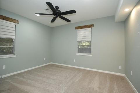 A photo of the primary bedroom that features carpet ceiling fan, and two windows for natural light. A photo of the primary bedroom that features carpet ceiling fan, and two windows for natural light.
