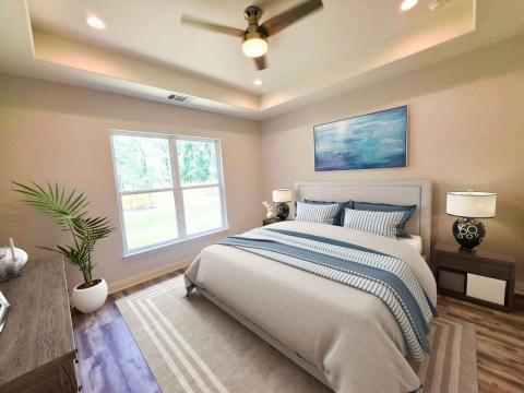Bedroom with a raised ceiling, wood finished floo