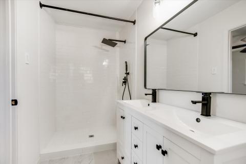 Full bath featuring double vanity, a stall shower