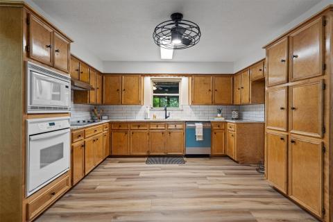 Kitchen featuring white appliances, brown cabinet