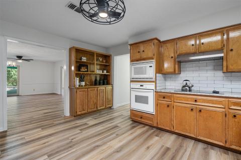 Kitchen with white appliances, range hood, brown 
