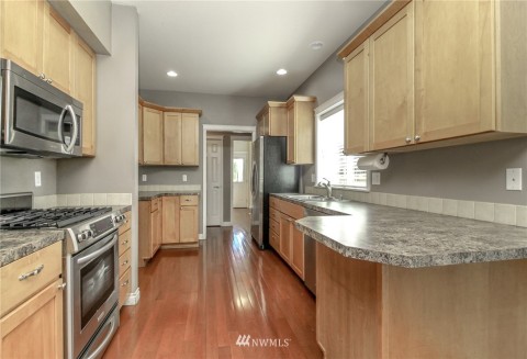 Large kitchen with counterspace galore. St St appliances & gas cooktop. Shown in center of photo is the door to the large pantry. Beyond is the utility room & backdoor.