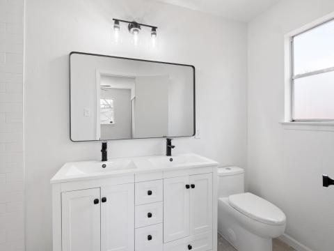 Full bath featuring a sink, toilet, and double va