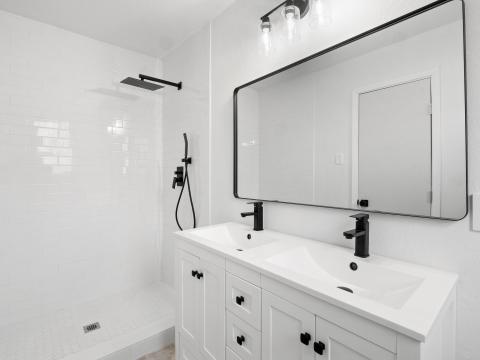 Bathroom featuring a sink, tiled shower, and doub