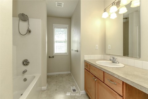 Second full bath with single sink and built-in vanity area.