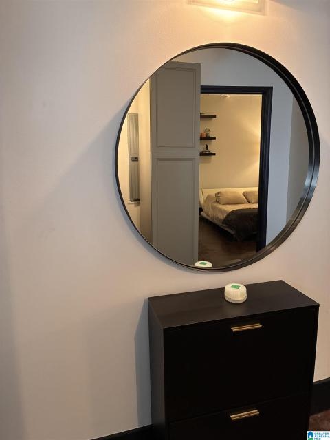 Contemporary round mirror with a black frame, mounted above a black storage console featuring gold-tone bar pulls