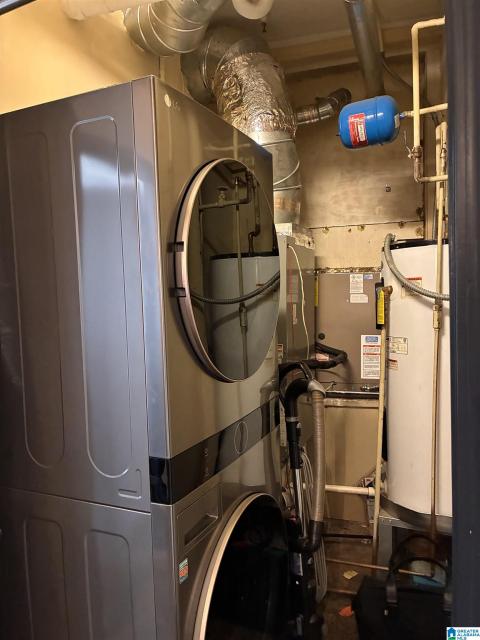 Dedicated utility area featuring a stacked washer and dryer unit, visible HVAC ductwork, and a water heater