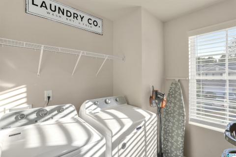 Dedicated laundry area featuring wire shelving, light-colored walls, and a window with horizontal blinds