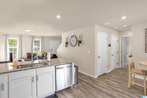 Open-concept living space with a kitchen island featuring a double-basin sink, stainless steel dishwasher, and stone-finish countertop